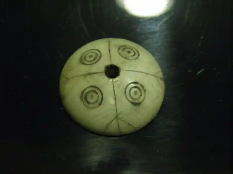 Solar disc with four solar symbols and a cross and a hole in the center